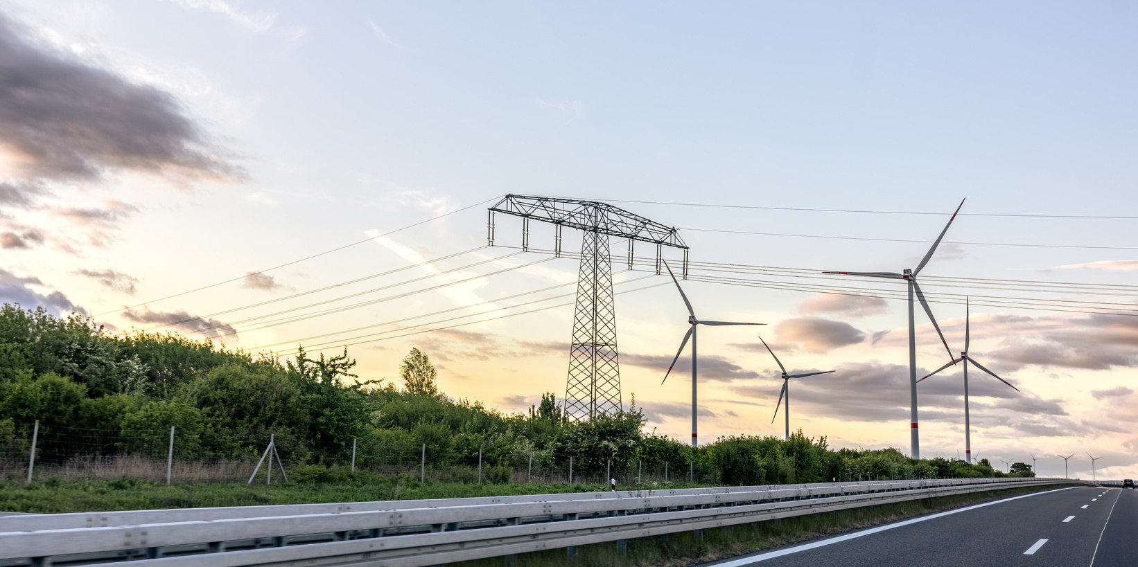 Hochspannungsmast und Windräder im Abendlicht an einer Autobahn – Motiv zum Forum Netzanschluss in Dresden